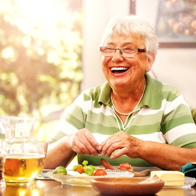 Senior woman with dentures in Carrollton smiling at dining table
