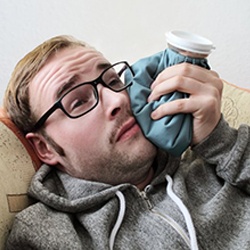 man holding an ice pack to his cheek