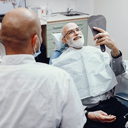 dental implant patient admiring his new smile in a mirror