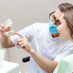 dentist showing a patient a model of a dental implant