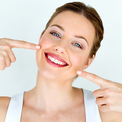 Woman pointing to her smile after cosmetic gum recontouring