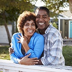 smiling man and woman standing in their front yard 