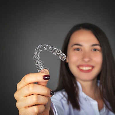 person holding their orthodontic aligners in front of them