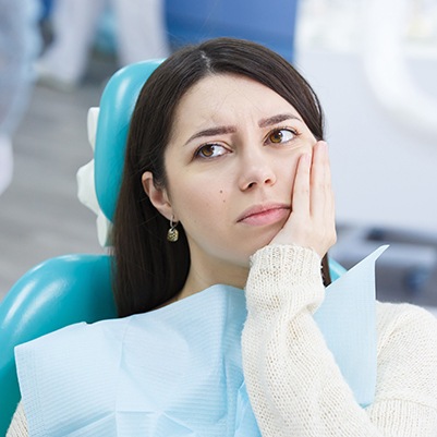 Woman at root canal appointment holding cheek