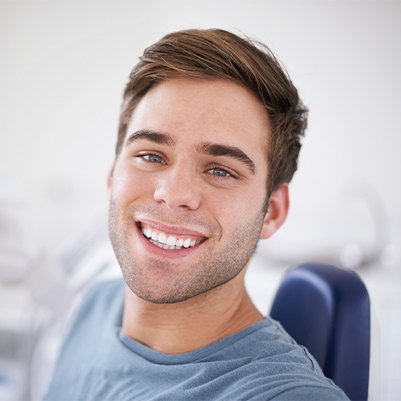 Young man in dental chair smiling after wisdom tooth extraction